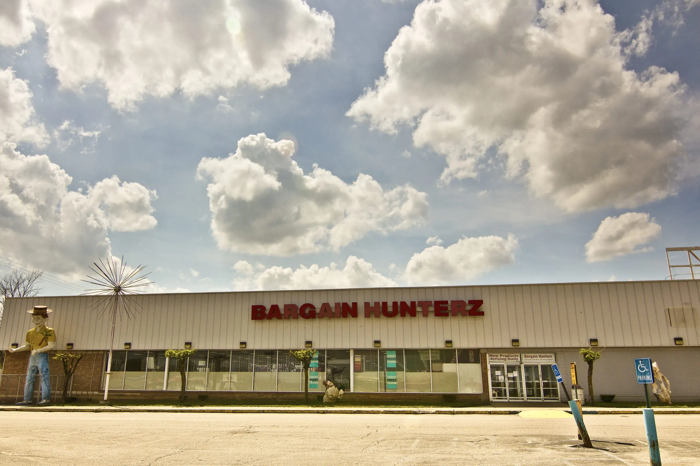 A low strip building with BARGAIN HUNTERZ across the front and an empty parking lot before it