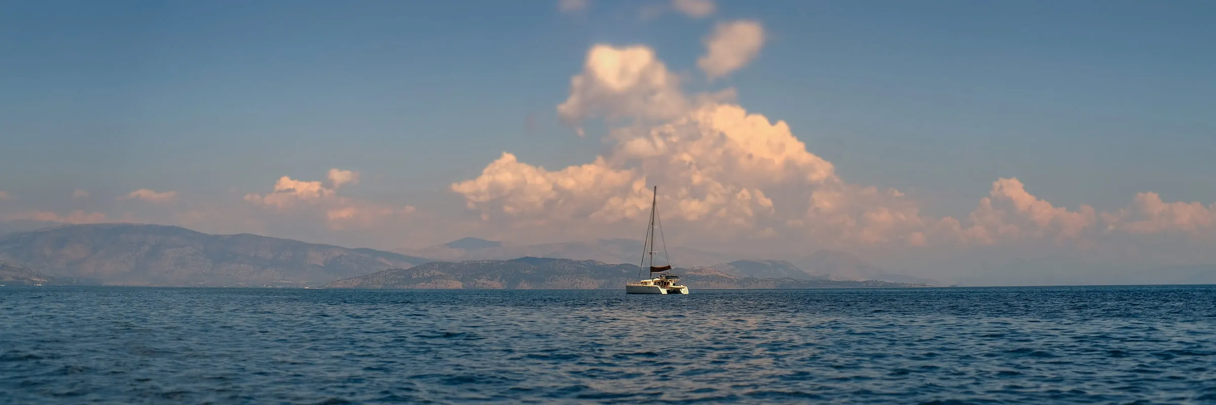 The Old Fortress of Corfu on its headland, a sailing boat crossing the water in front