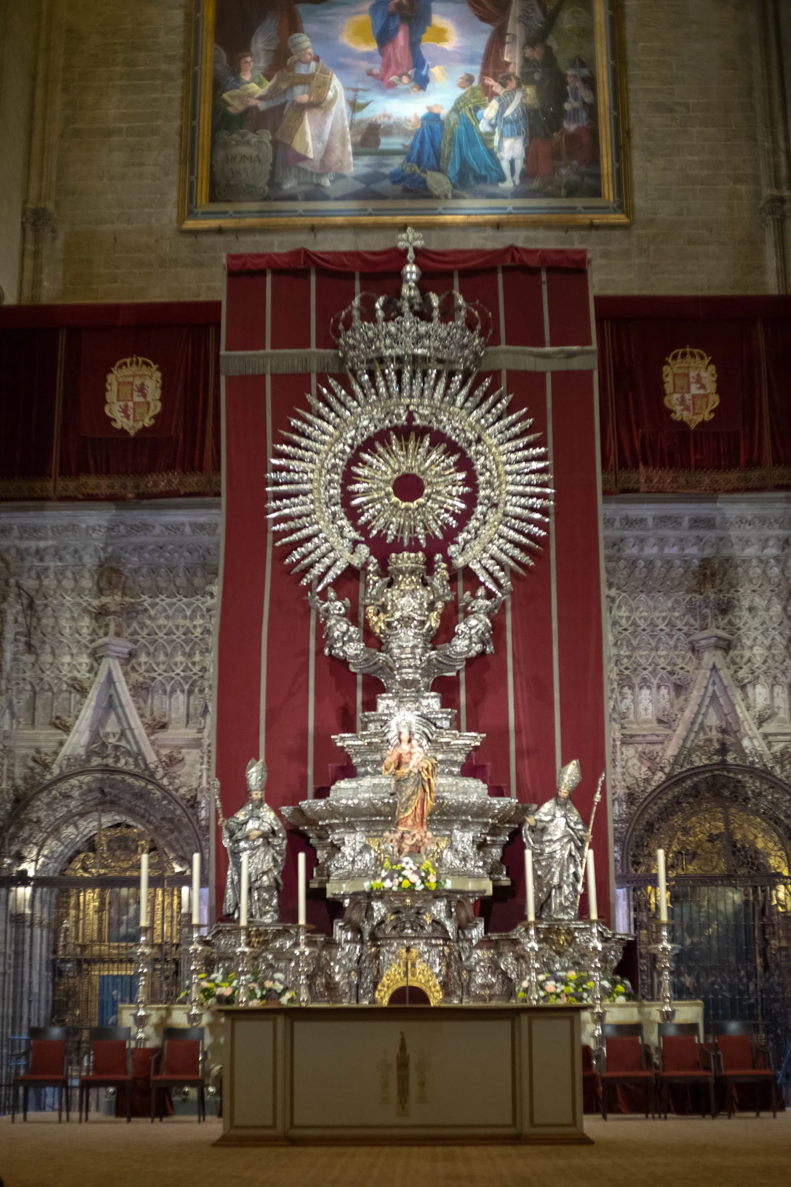 The silver monstrance and altarpiece inside Seville Cathedral, framed by a red hanging