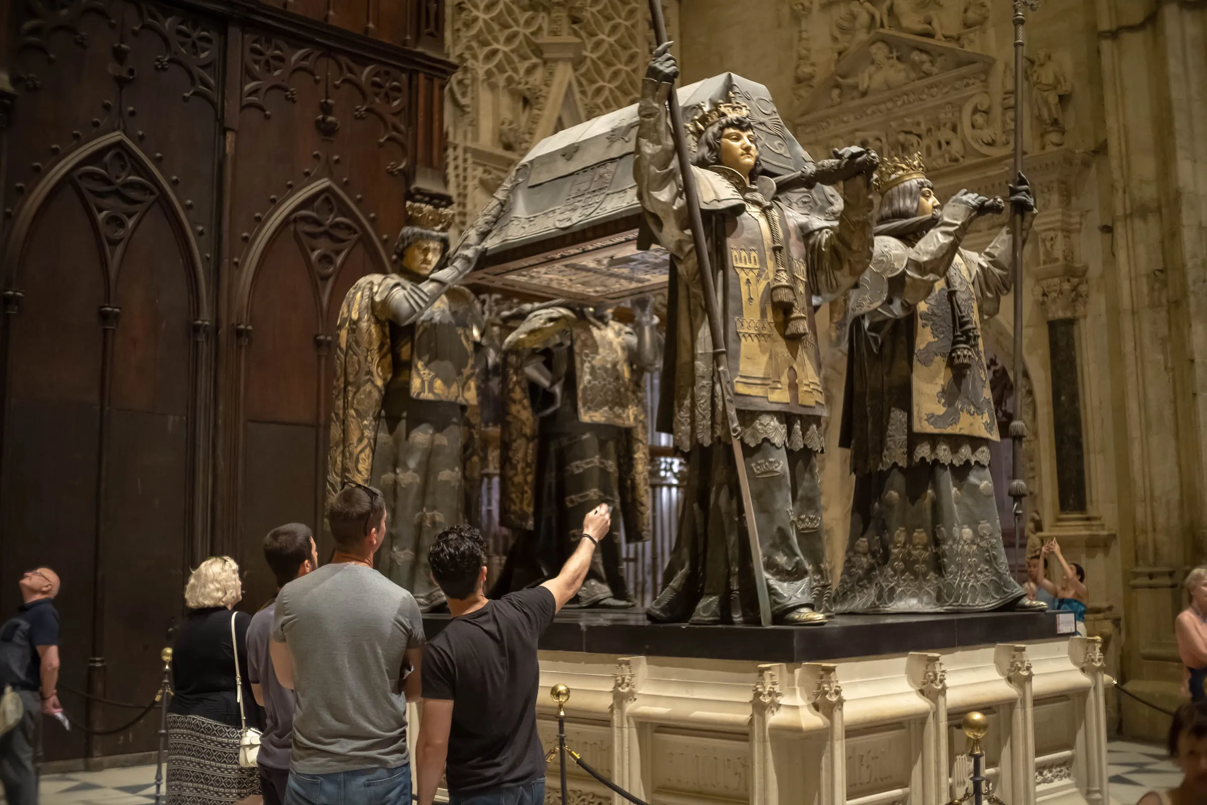 Visitors standing at the tomb of Christopher Columbus, one reaching up to touch a bearer