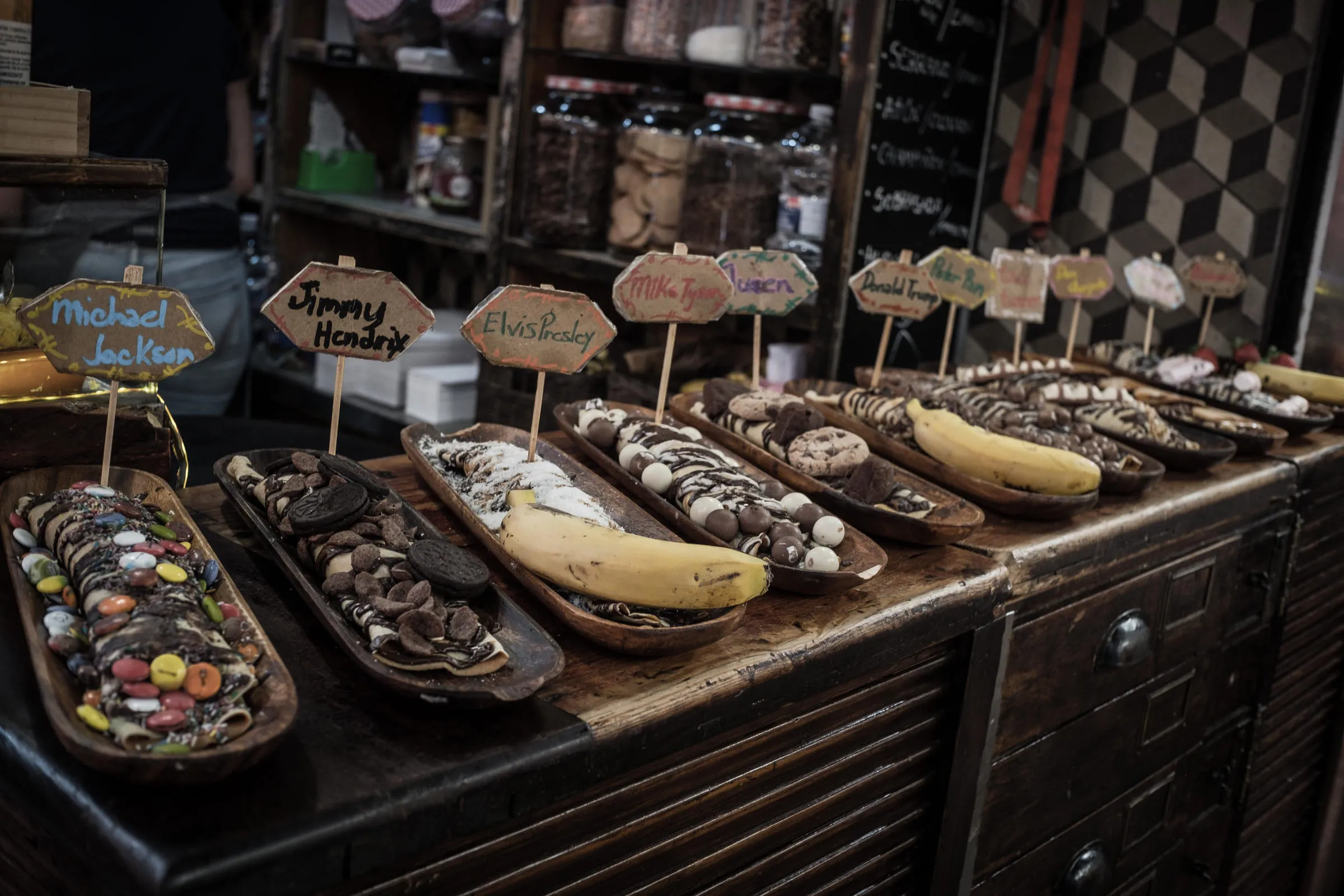 A chocolate shop counter, trays of sweets labelled with handwritten musicians' names
