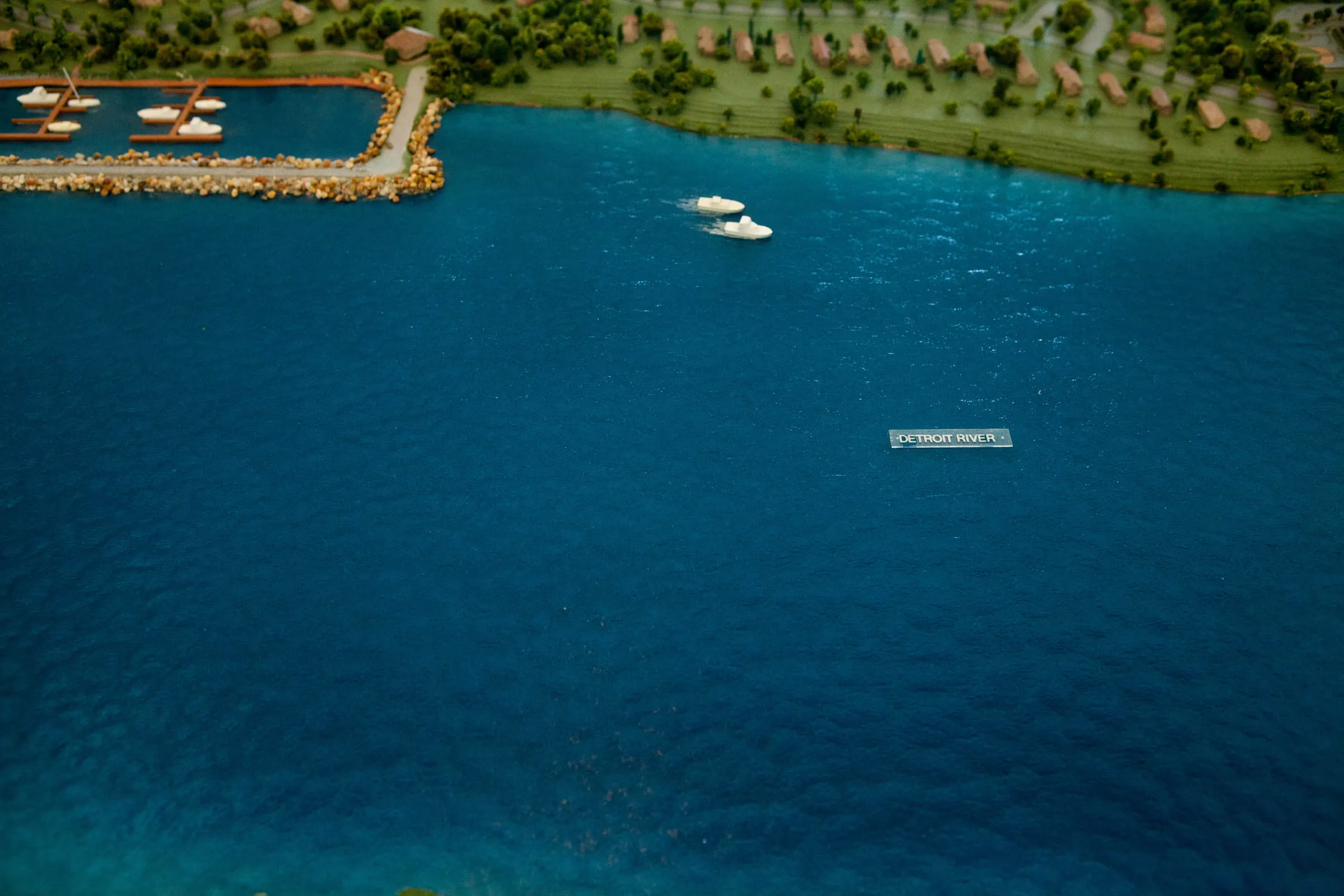 The model's stretch of blue river with a tiny boat crossing it
