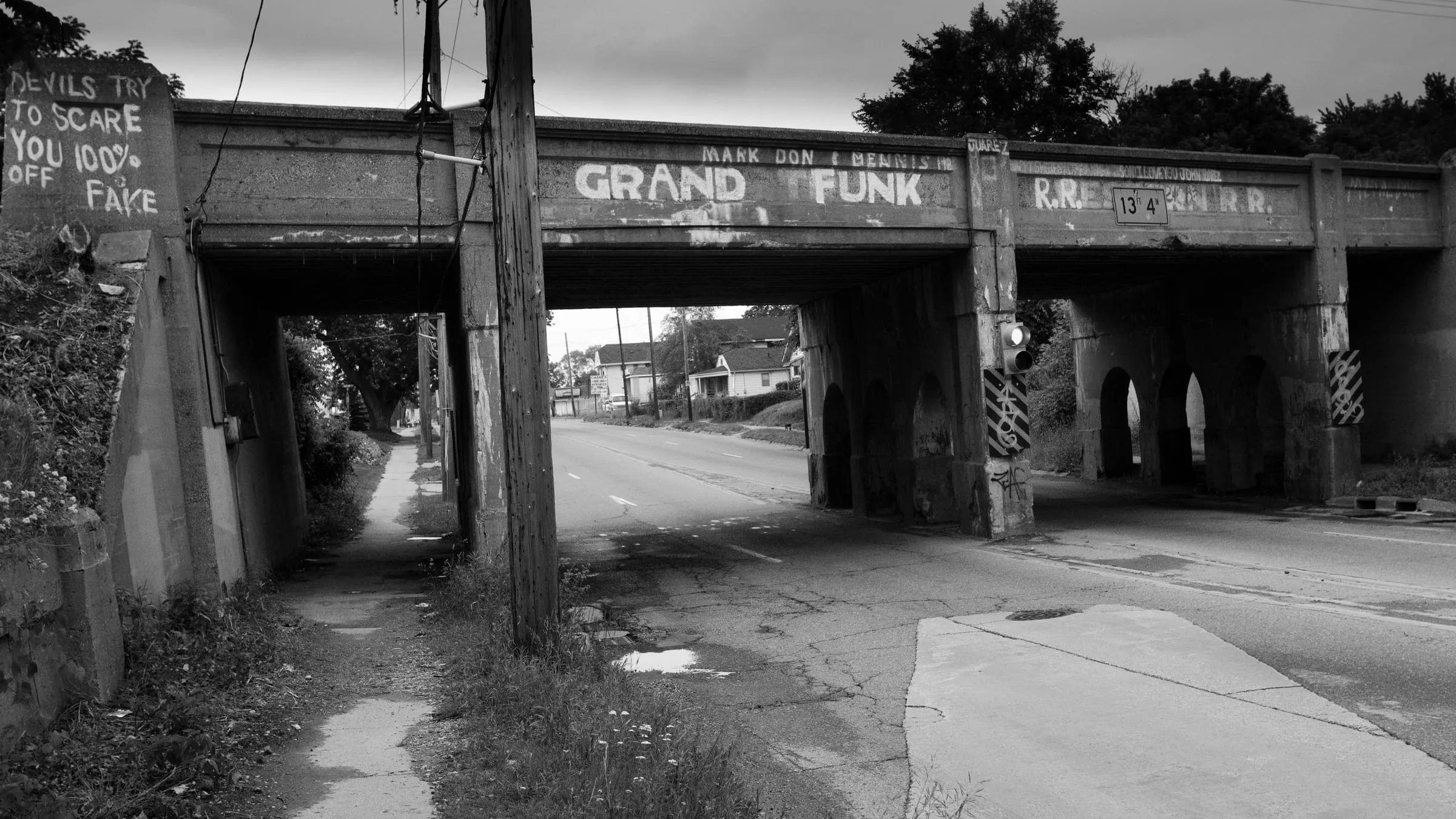 Black and white view of a railway underpass with GRAND FUNK painted across the bridge