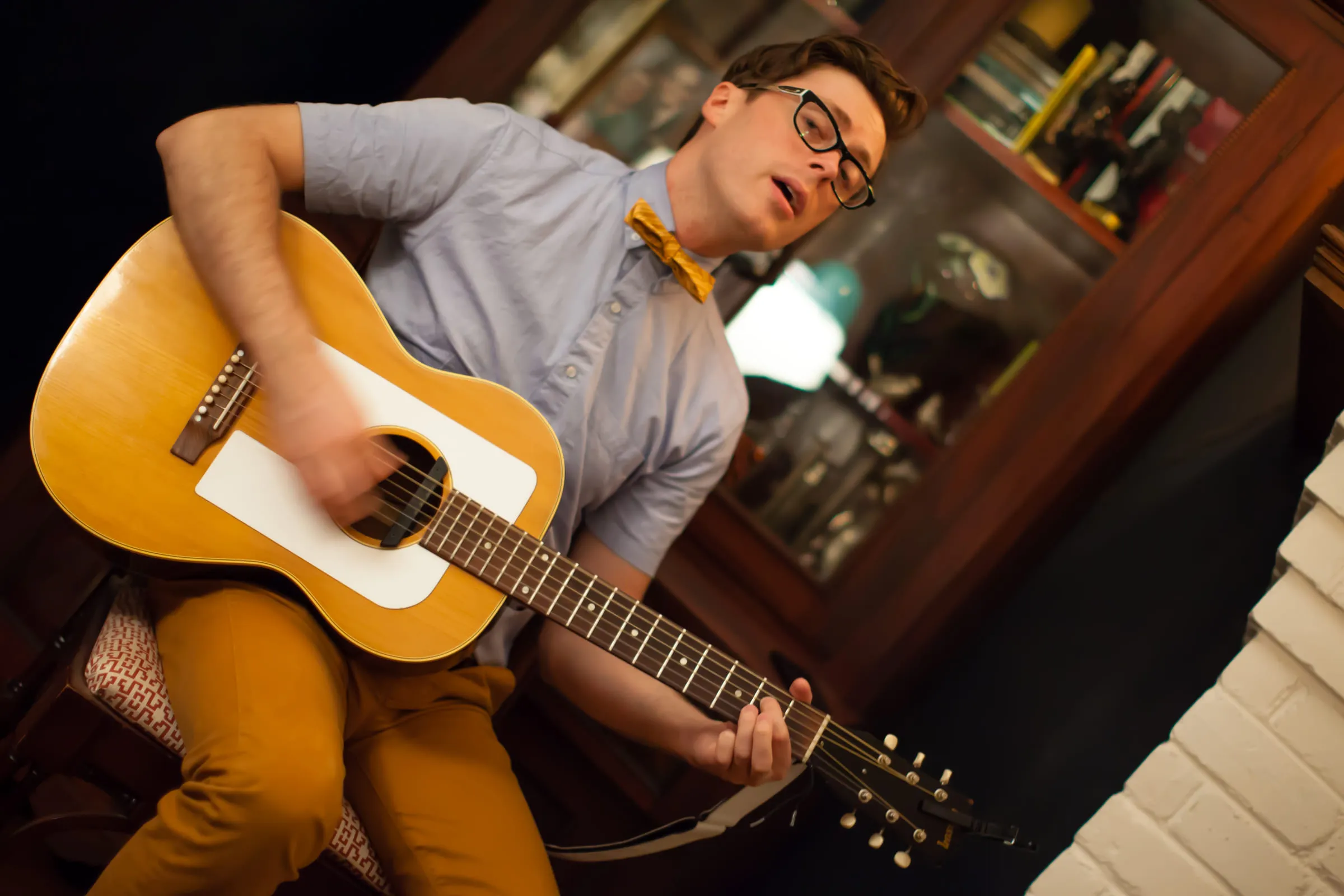 Jeremy Messersmith playing acoustic guitar, shot at a tilt, singing toward the microphone