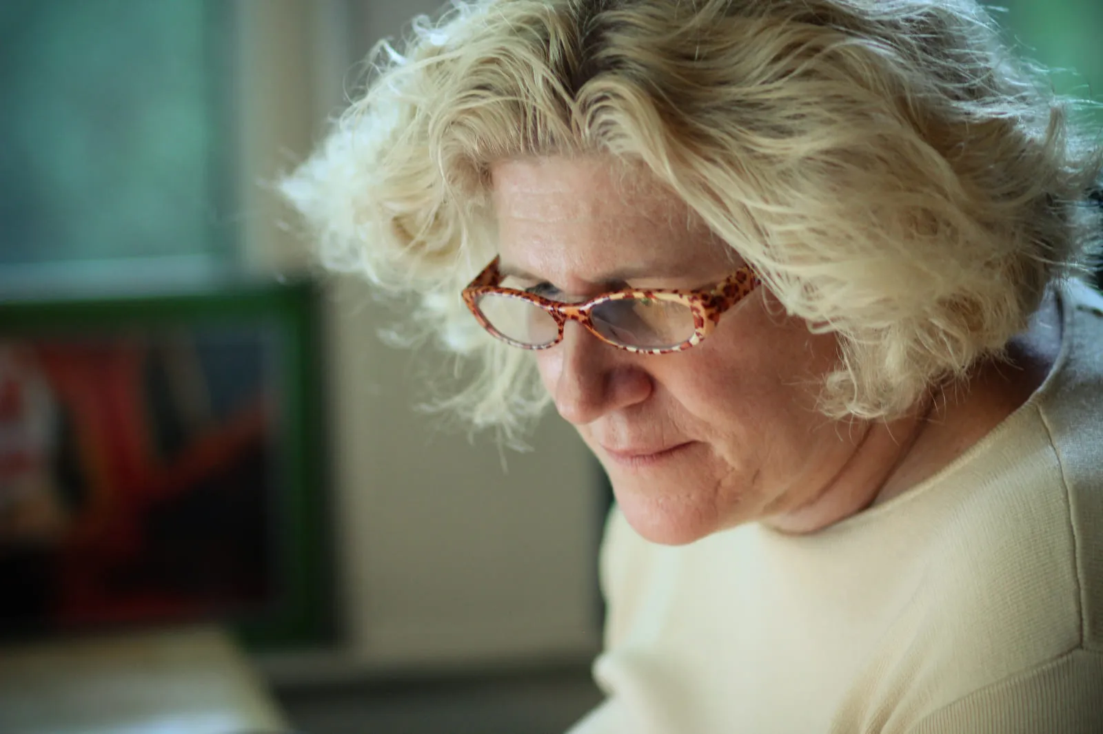 Lisa looking down through patterned glasses, white hair catching the light