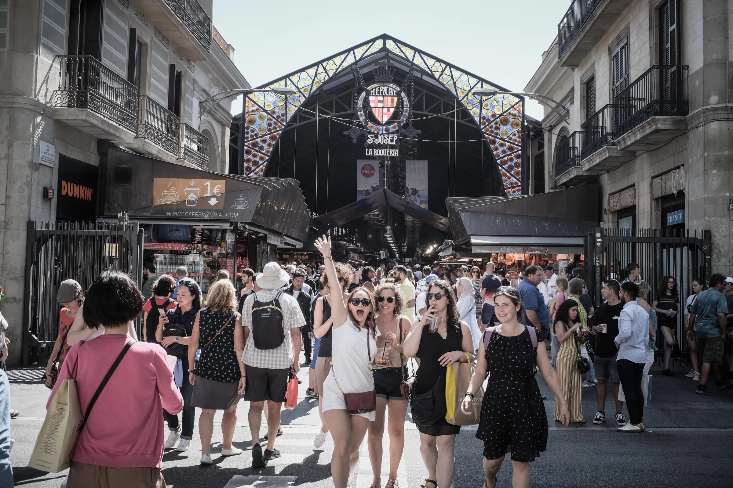 A crowded market street, one person in the crowd waving toward the camera