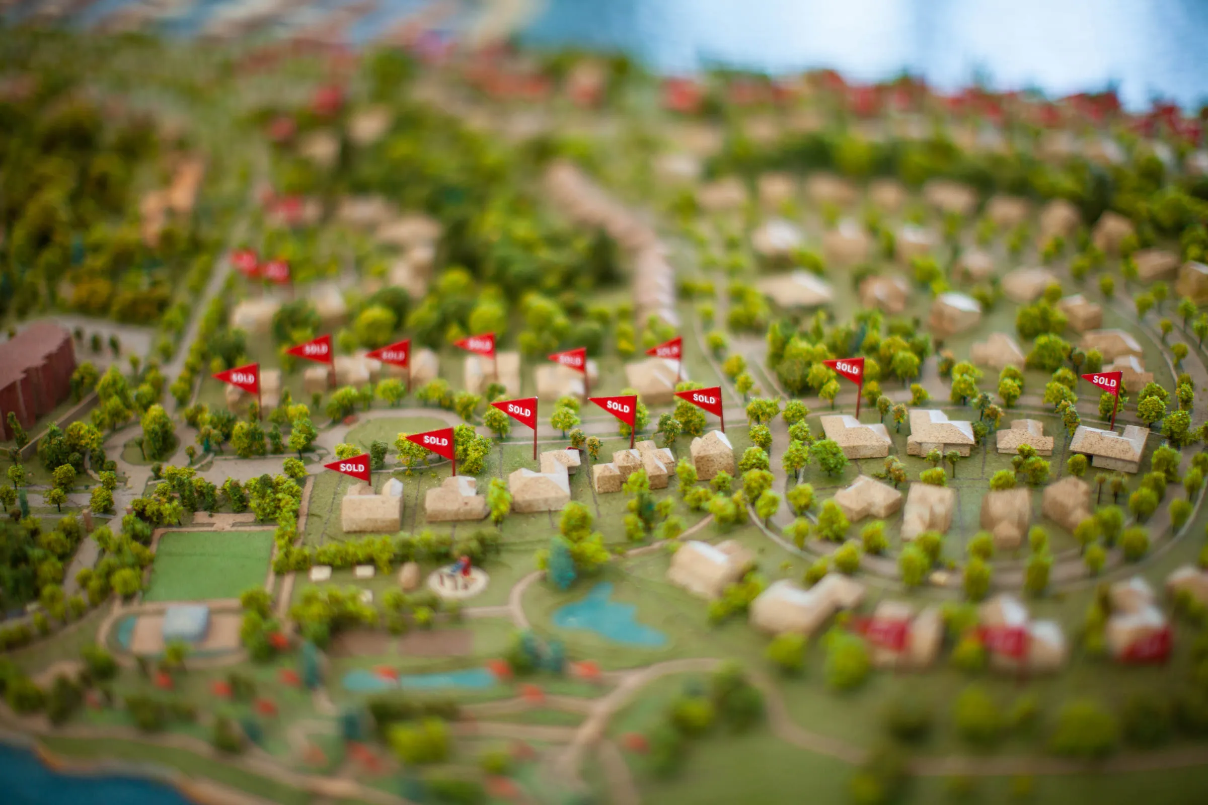 Small red SOLD flags planted across the model's housing lots