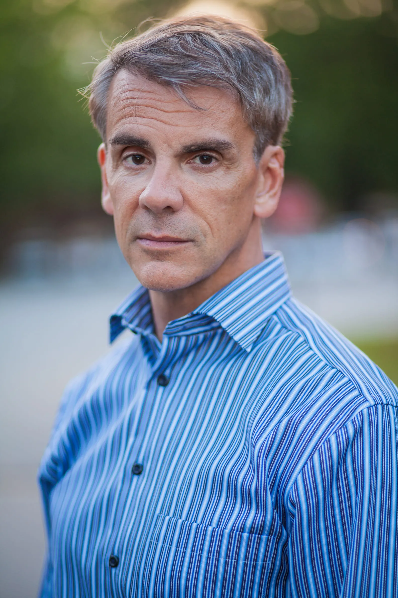 Portrait of Philip Powell in a blue striped shirt, looking directly at the camera