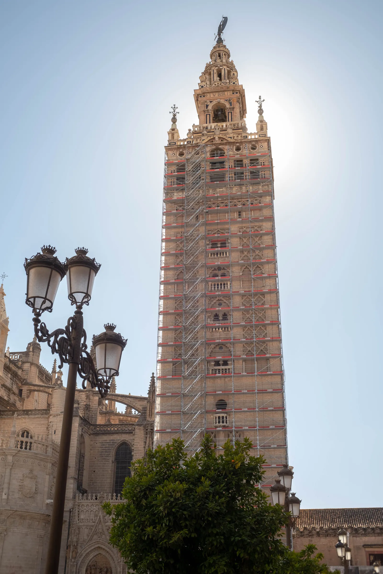 The Giralda bell tower under scaffolding, shot from below with the sun behind it